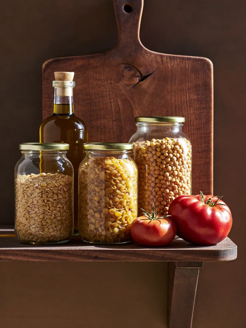 Barattoli di legumi, riso, pasta e olio in una dispensa rustica