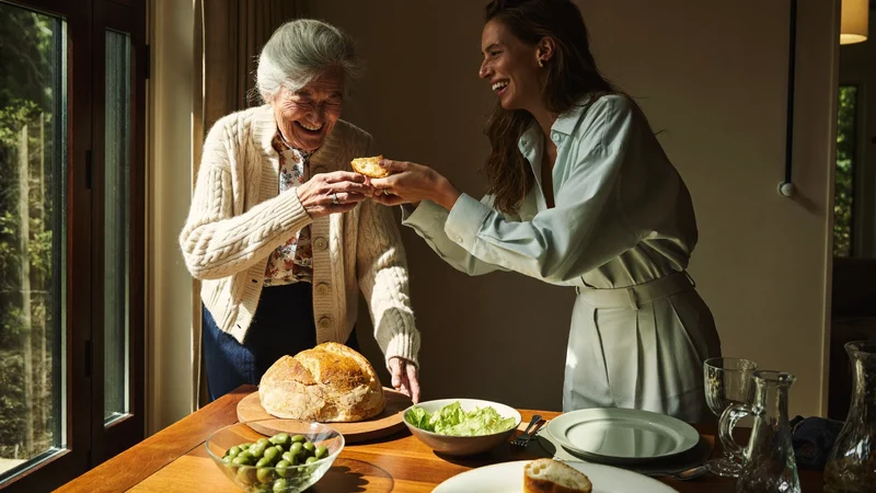 Nonno e nipote che apparecchiano insieme con pane, olive e insalata